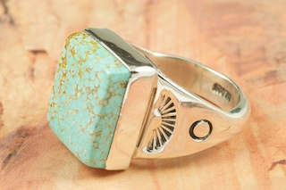 Genuine Number 8 Turquoise set in Sterling Silver Ring. The Number 8 mine is located in Eureka County Nevada. Since 1976 there has been no Number 8 Turquoise mined. There is however, an existing stock pile that Mr. Dowell Ward, the last owner of the Number 8 mine, had stocked away for later sorting. The Turquoise is a collector's item--because once the reserve is gone there will be no more material released onto the market. The Gold Mining Company owns the claim to the Number 8 mine and it has been swallowed up by the gold mining operations. This is some of the last Number 8 Turquoise to be had and will be a great addition to your collection. Created by Navajo Artist Phillip Sanchez. Signed by the artist.
